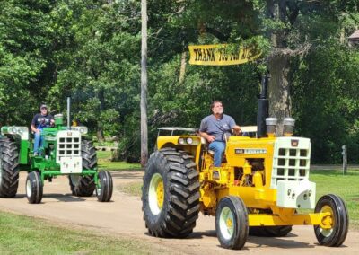 Two men riding yellow and green color tractor